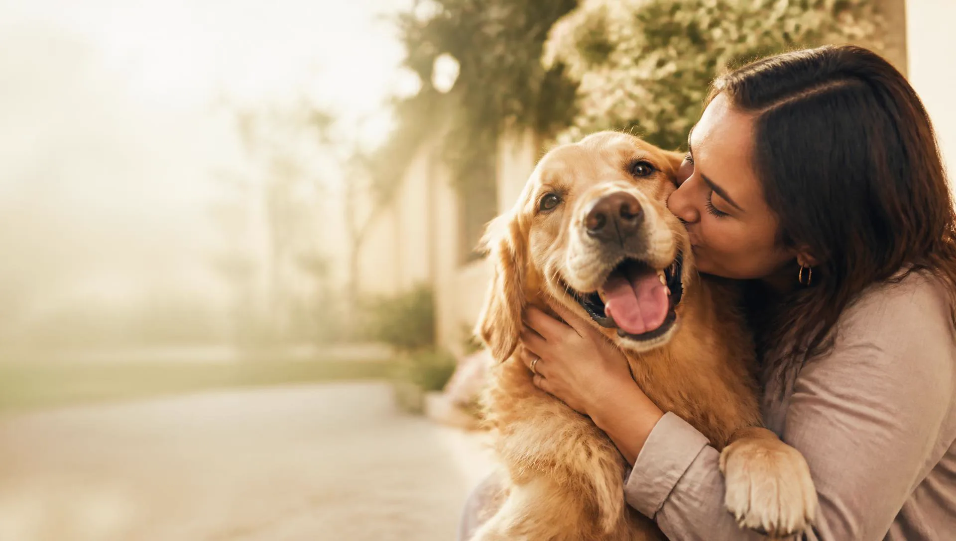 Pet owner crouching beside her dog on a riverside promenade in northern Portugal at golden hour